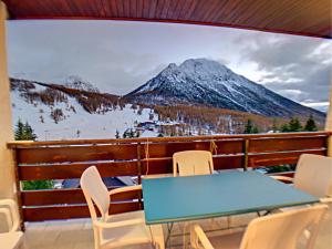 uma varanda com uma mesa e cadeiras e uma montanha em La Durance em Montgenèvre