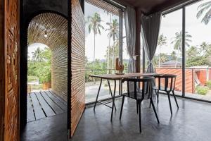 een eetkamer met een tafel, stoelen en ramen bij Coconutnoom Ko Phangan in Thongsala