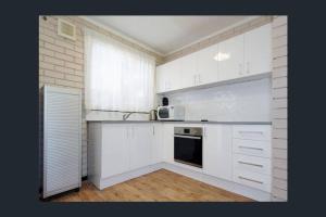 uma cozinha com armários brancos e um micro-ondas em Affordable Apartment close to city and Beaches em Perth