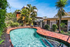 a swimming pool in front of a house at Noosa Rest in Noosa Heads