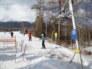 ein Kind auf Skiern auf einem Skilift im Schnee in der Unterkunft Apartmán B 101 Vysoké Tatry in Starý Smokovec