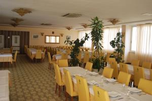 a restaurant with white tables and yellow chairs at Hotel Calabresi in San Benedetto del Tronto