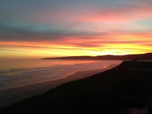 a sunset over a beach with the ocean at Dolphin Dunes Guesthouse in Wilderness