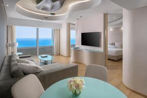 a living room with a couch and a television at Rodos Palace Hotel in Ixia