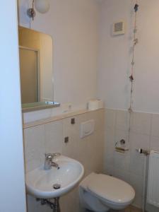 a bathroom with a sink and a toilet and a mirror at Apartment Muschel im Gästehaus Heeren in Krummhörn