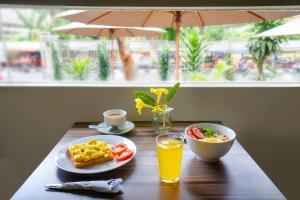 a table with breakfast food and a glass of orange juice at LeGreen Suite Pejompongan in Jakarta