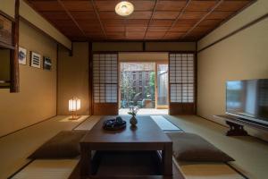 sala de estar con mesa y TV en Gion Shirakawa Kouki Machiya House, en Kioto