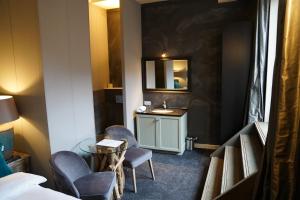 ein Hotelzimmer mit einem Waschbecken, Stühlen und einem Spiegel in der Unterkunft Huis van Bewaring in Almelo