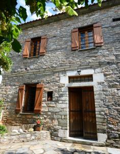 un vecchio edificio in pietra con finestre con persiane marroni di Aronia Stone House a Lafkos