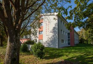un edificio en un parque con un árbol en Bergers Airporthotel Memmingen, en Memmingerberg