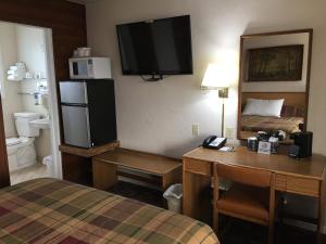 a hotel room with a desk and a bed and a room with a television at Southsider Motel in Coos Bay