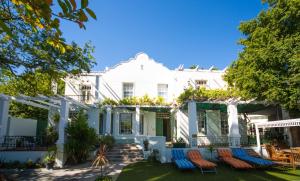 ein weißes Haus mit Stühlen im Hof in der Unterkunft Mountain Manor Guest House & Executive Suites in Kapstadt