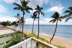 uma varanda com vista para a praia e palmeiras em Nani Kai Hale em Kihei