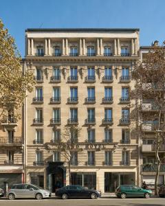 un grand bâtiment avec des voitures garées devant lui dans l'établissement Grand Hôtel Clichy Paris, à Clichy