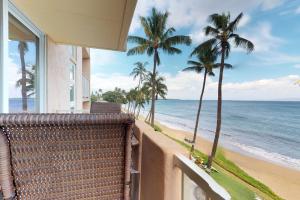 a balcony with a view of the ocean and palm trees at Nani Kai Hale in Kihei