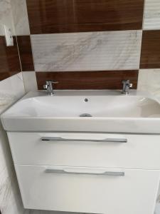 a white sink with two faucets in a bathroom at Centrum Apartman LEYLA 5 in Bardejov +30 photos