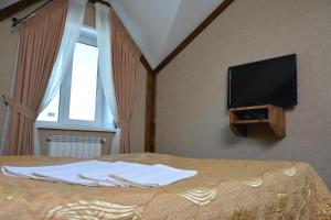 a bedroom with a bed with a flat screen tv at Tropicana Inn in Uralsk +18 photos