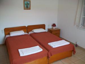a bedroom with two beds with red sheets at Nicolas Rooms in Fiskardo