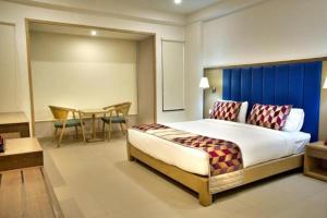 ein Schlafzimmer mit einem großen Bett und einem Tisch in der Unterkunft Purple Cloud Hotel in Devanhalli