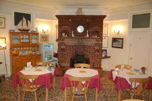 a dining room with two tables and a fireplace at Trevarner Guest House in Fareham