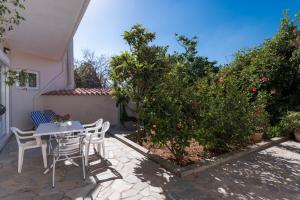 a patio with a table and chairs and a tree at Niki's Apartment in Palaiochóra +6 photos