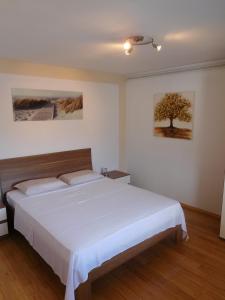 a bedroom with a white bed and a tree on the wall at Villa Marija in Korčula