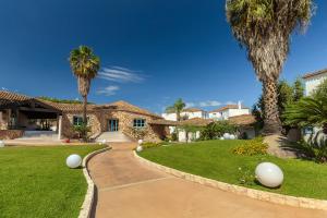 a house with palm trees and a driveway at Corte Bianca - Adults Only & SPA - Bovis Hotels in Cardedu