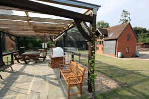 a wooden pergola with a bench on a patio at Upper Neatham Mill in Alton