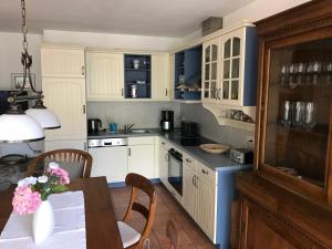 a kitchen with white cabinets and a table with flowers at "Kombüse" by Ferienhaus Strandgut in Born