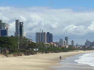 uma pessoa andando na praia em frente a uma cidade em Apartamento Dona Elvira em Piçarras