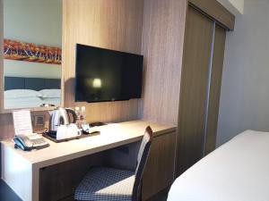 a hotel room with a desk with a television and a bed at KSL Hot Spring Resort in Johor Bahru