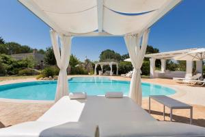 a bed in a tent in front of a swimming pool at Trullo Dei Messapi in Ceglie Messapica