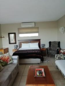een slaapkamer met een bed en een bank bij Beachfront Cabanas in Amanzimtoti