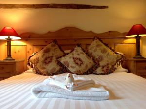 a bed with a towel on it with two lamps at Slapton Manor in Towcester