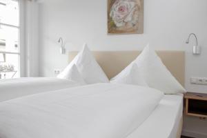 a white bed with white pillows in a bedroom at Hotel zur Sonne in Rimsting +54 photos