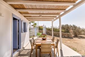 einen Holztisch und Stühle auf einer Terrasse mit einer hölzernen Pergola in der Unterkunft My Chorio Mykonos Country Summer House in Platis Gialos