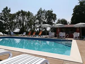 a large swimming pool with chairs and umbrellas at Isola Di Wight in San Michele al Tagliamento +23 photos
