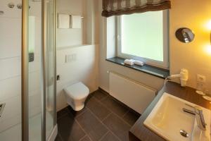 a bathroom with a toilet, sink and tub at Bergers Airporthotel Memmingen in Memmingerberg