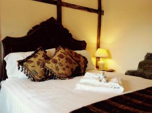 a bed with a pile of pillows and a towel at Slapton Manor in Towcester