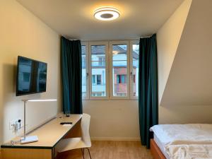 a bedroom with a desk and a bed and a window at Royal Hotel Zurich in Zurich