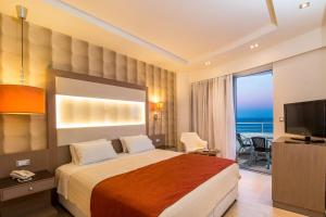 a hotel room with a bed with a view of the ocean at Pegasos Deluxe Beach Hotel in Faliraki