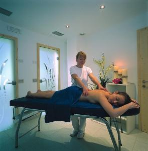 a woman giving a man a massage in a room at Piccolo Hotel in Canazei