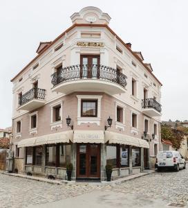 a large white building with a balcony on a street at Hotel Vila Sigal Korce in Korçë