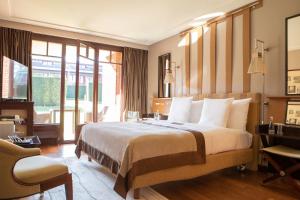 a hotel room with a bed, chair, desk and a window at La Réserve Genève Hotel & Spa in Geneva