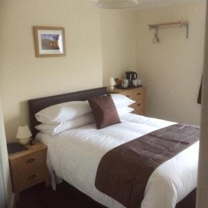 a bedroom with a large bed with white sheets and pillows at Mill Croft Bed and Breakfast in Goathland