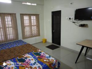 a bedroom with a bed and a flat screen tv at Hotel Woodlands in Chottanikara +12 photos