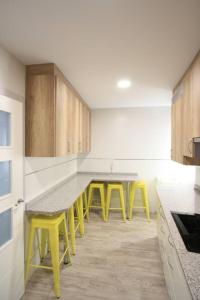 una cocina con mesas amarillas y taburetes amarillos en Apartamento entero 4HB centro Salamanca by Batuecas, en Salamanca