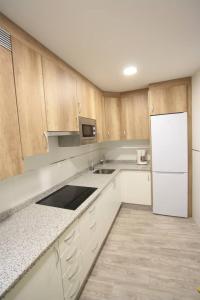 eine Küche mit Holzschränken und einem weißen Kühlschrank in der Unterkunft Apartamento entero 4HB centro Salamanca by Batuecas in Salamanca