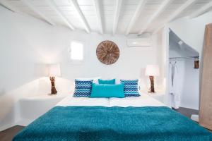 a white bedroom with a bed with blue pillows at Absolute Mykonos Suites & More in Mýkonos City