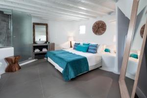 ein weißes Schlafzimmer mit einem Bett und einem Spiegel in der Unterkunft Absolute Mykonos Suites & More in Mykonos Stadt